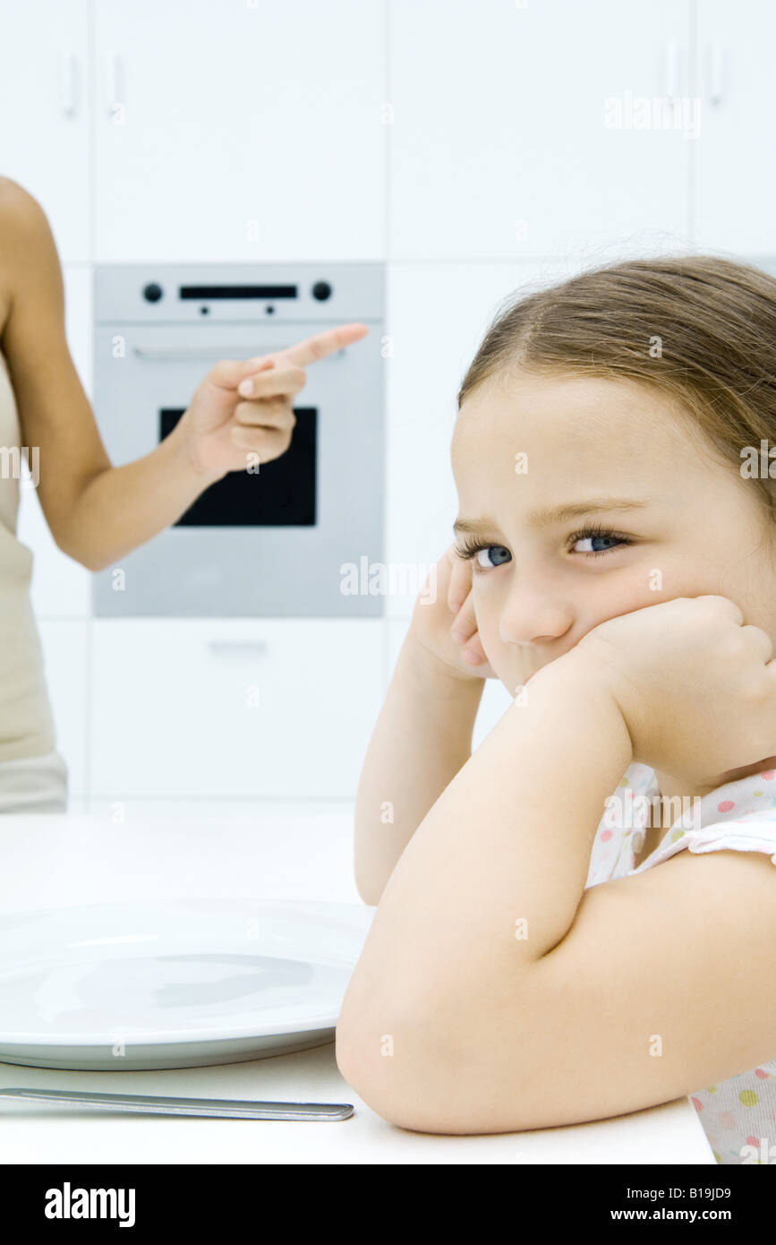 Mädchen am Küchentisch, Zittern der Finger, Mutter schmollend beschnitten Ansicht Stockfoto