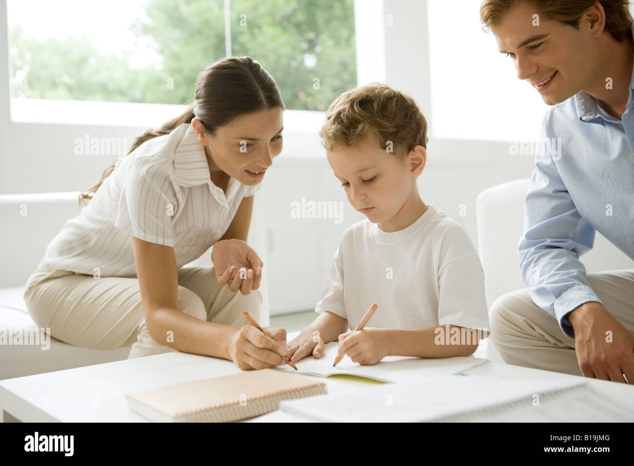 Kleiner Junge mit seinen Hausaufgaben zu helfen Eltern Stockfoto