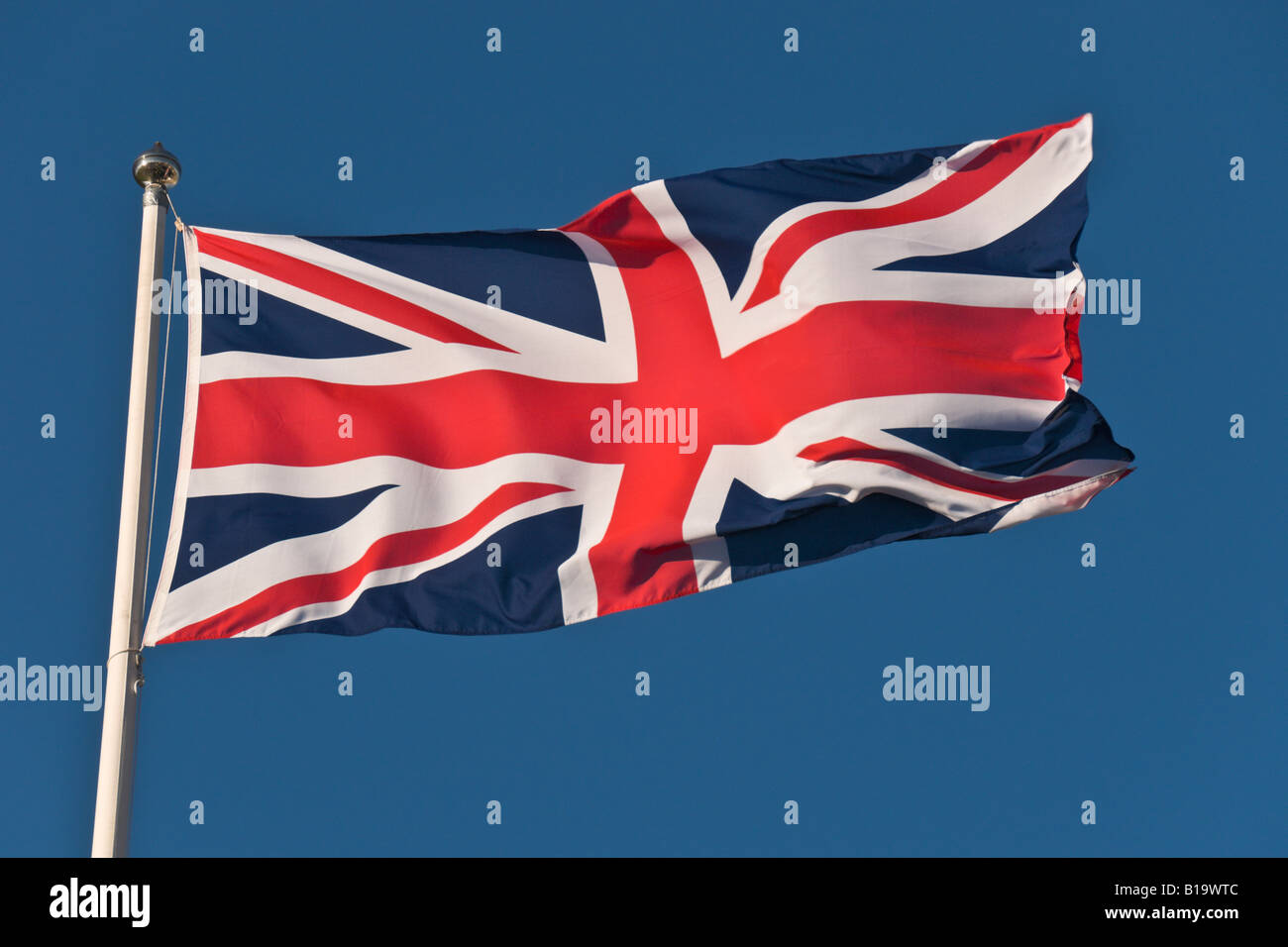 Ein Union Jack oder die Flagge von Großbritannien Blowing In The Wind auf blauen Himmelshintergrund. Stockfoto