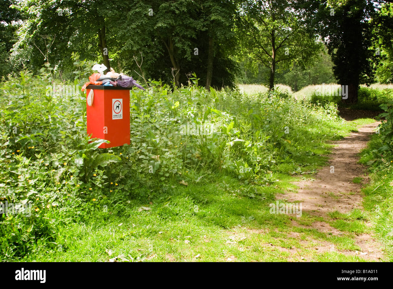 Sehr stinkende und überquellenden Hundeabfallbehälter neben einem Fußweg auf dem Lande Stockfoto