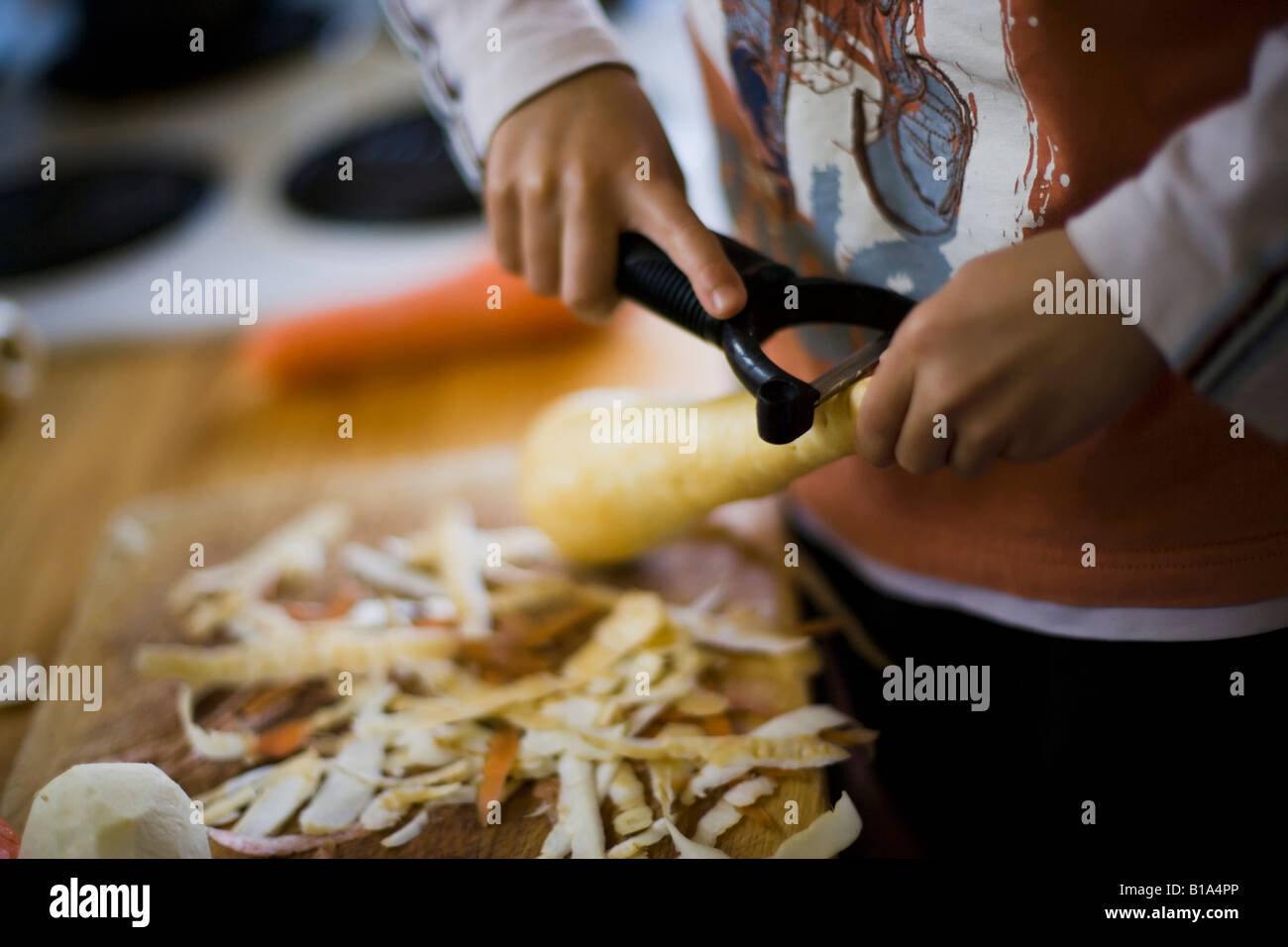 Kind hilft mit peeling Gemüse für Sonntag Braten Abendessen Stockfoto
