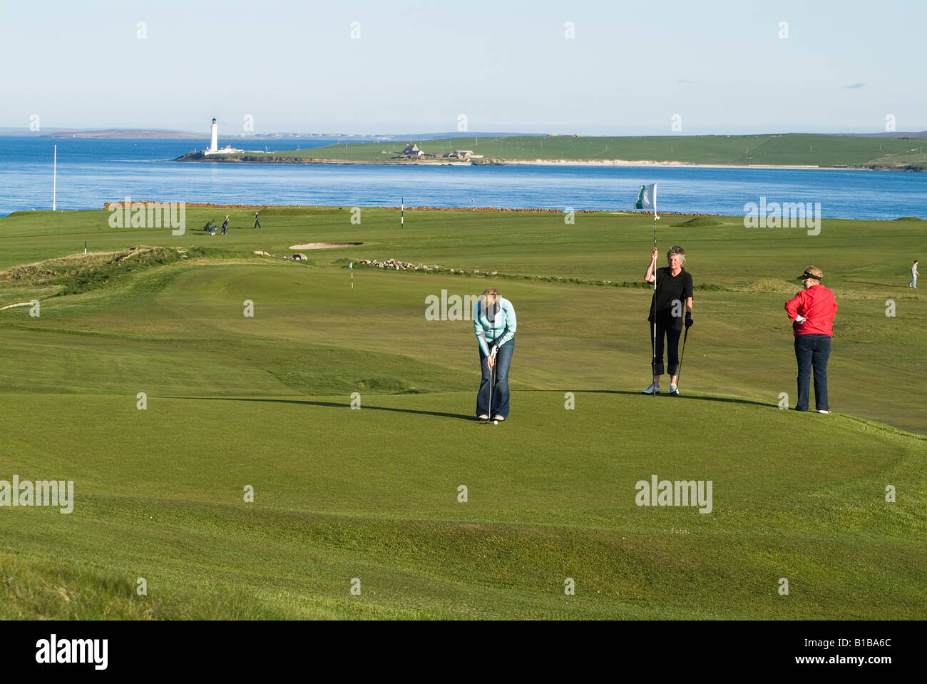 dh Stromness Golf Course STROMNESS ORKNEY Frau schoss Golf Putting Green Hole Flag Scapa Flow uk Schottland Damen Golf Frauen zusammen Golfer Stockfoto