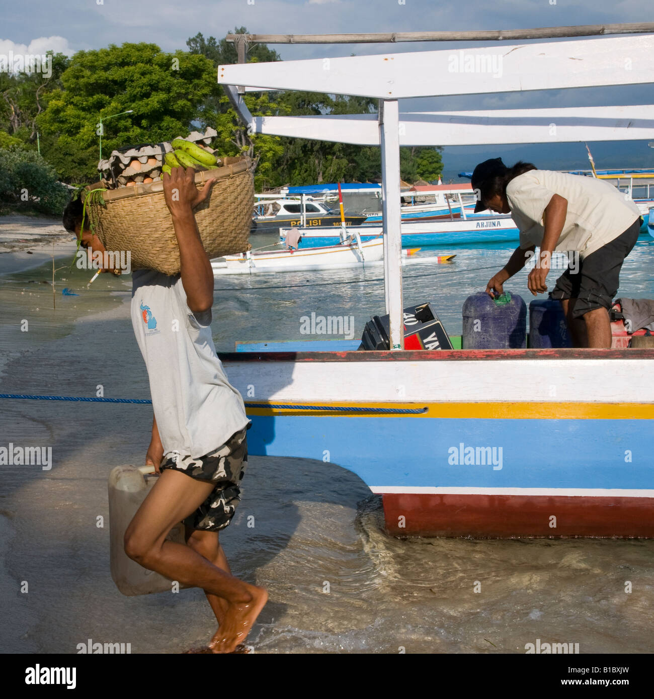 Indonesien Lombok Gili Air Insel Mann, der Lebensmittel-Versorgung vom Boot in großen Korb auf seinen Schultern trägt Stockfoto