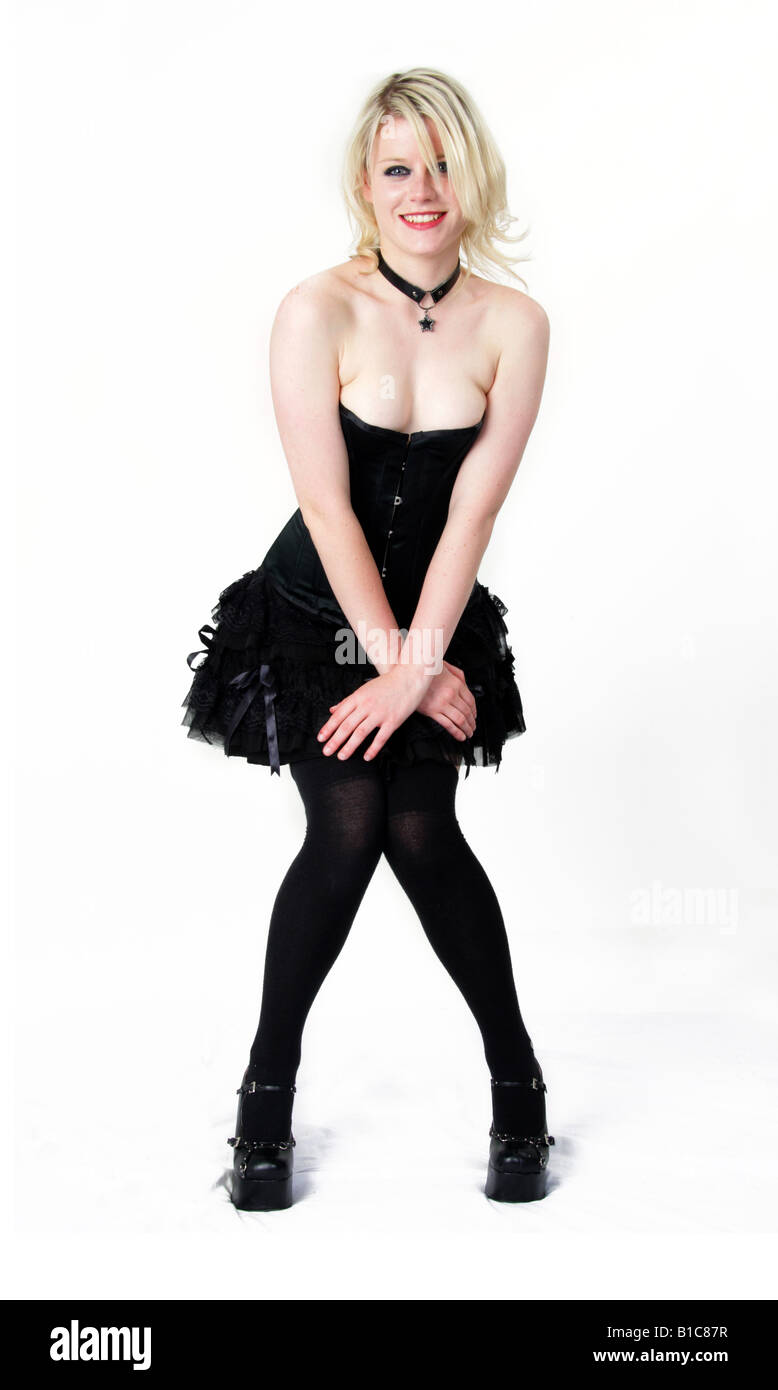 Blondes Mädchen in einem schwarzen Bask und geschichteten Rock in einer frechen Pose Stockfoto
