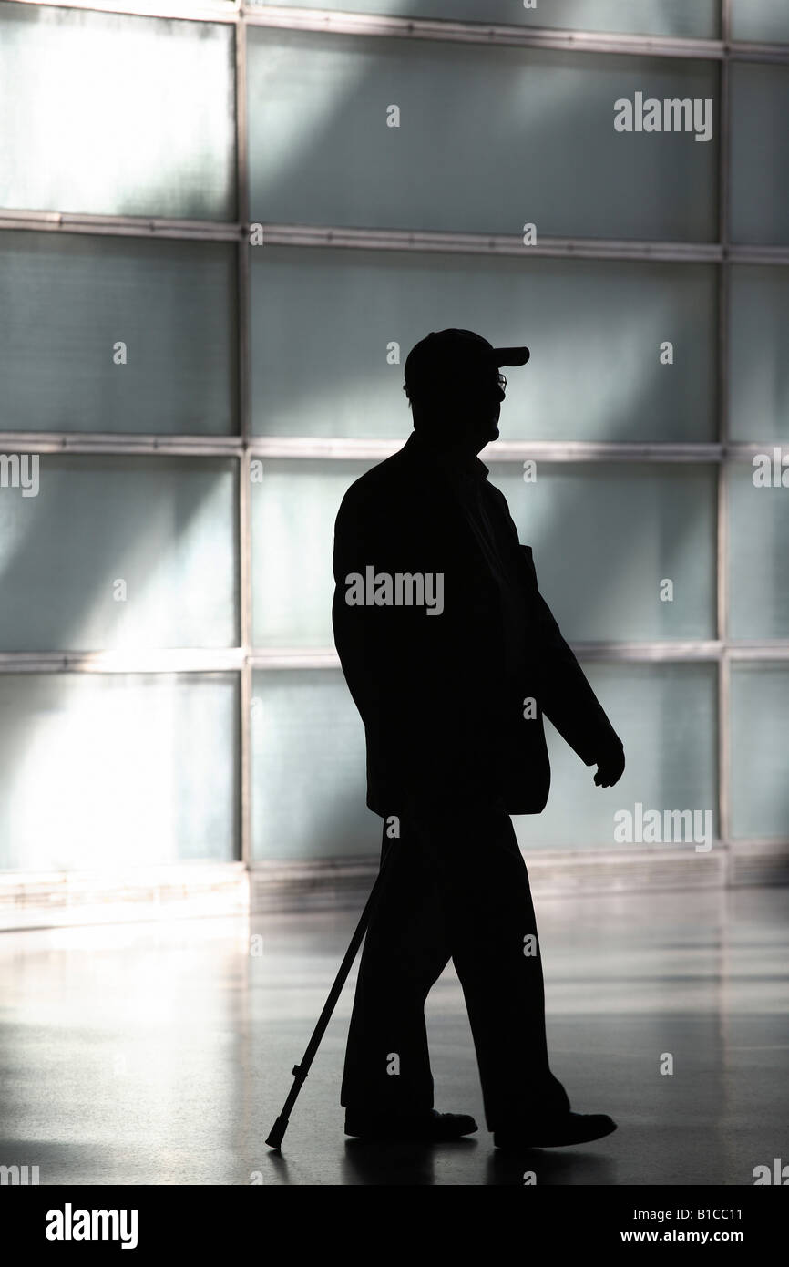 Silhouette eines älteren Mannes mit einem Gehstock und Baseball-cap Stockfoto