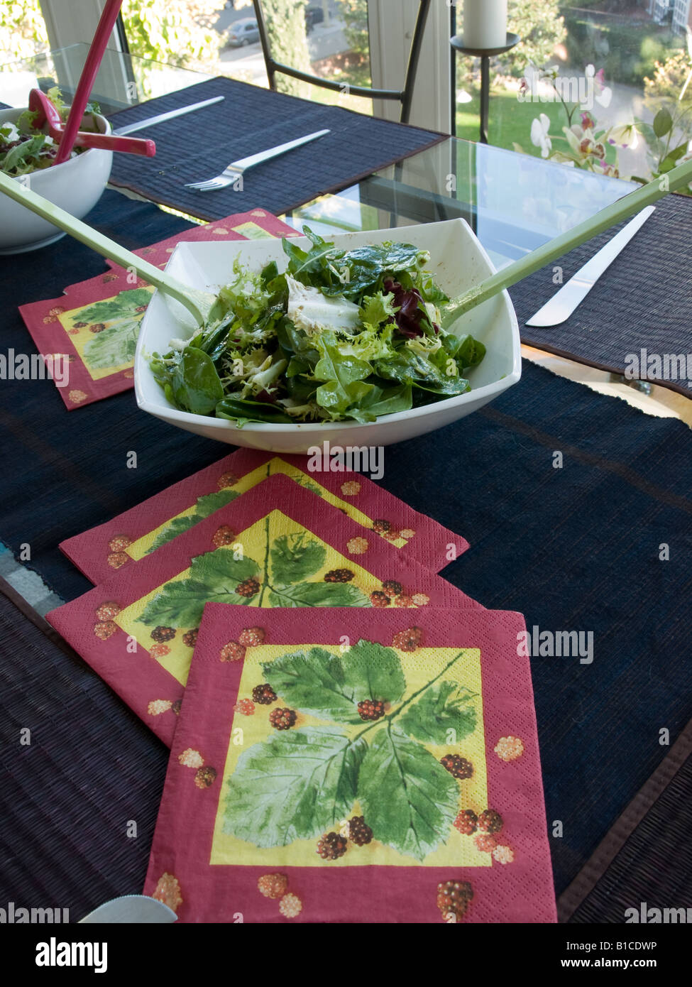 Teller mit grünem Salat auf einem Tisch bedeckt mit bunten Servietten Stockfoto