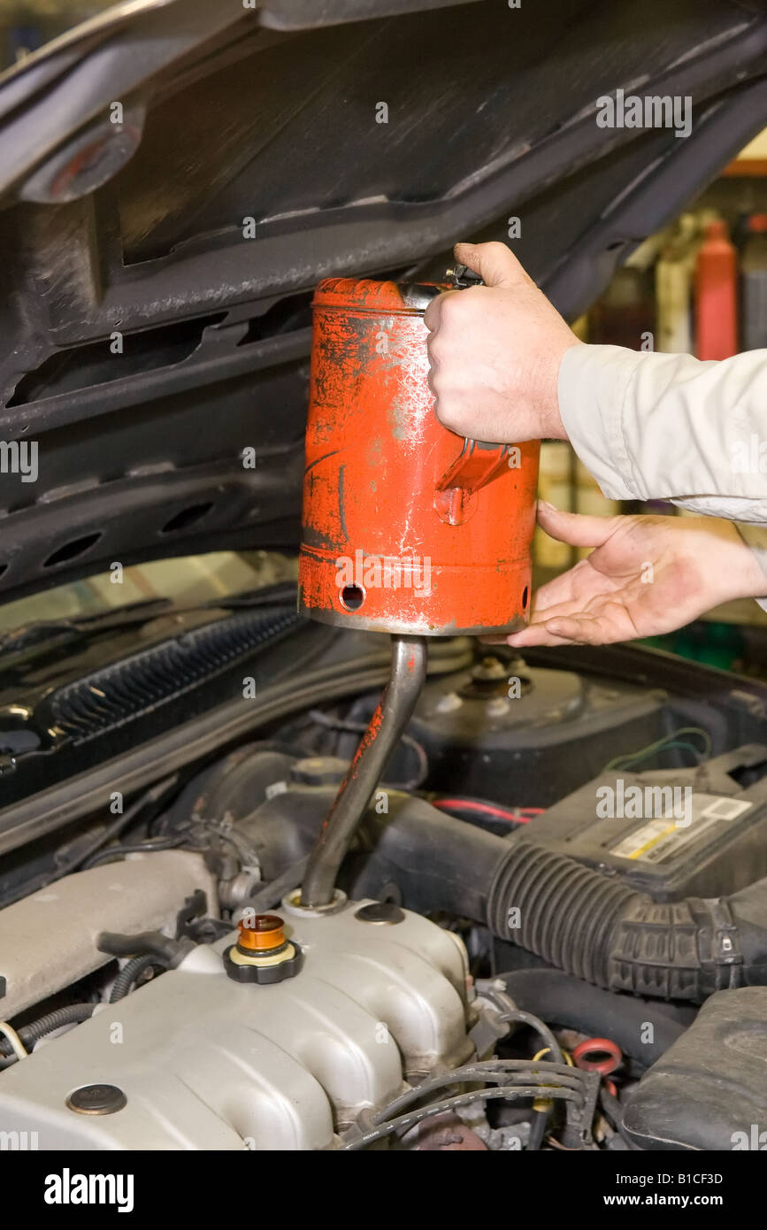 Mechaniker der Ölwanne während ein Automobil Öl nachfüllen ändern Stockfoto