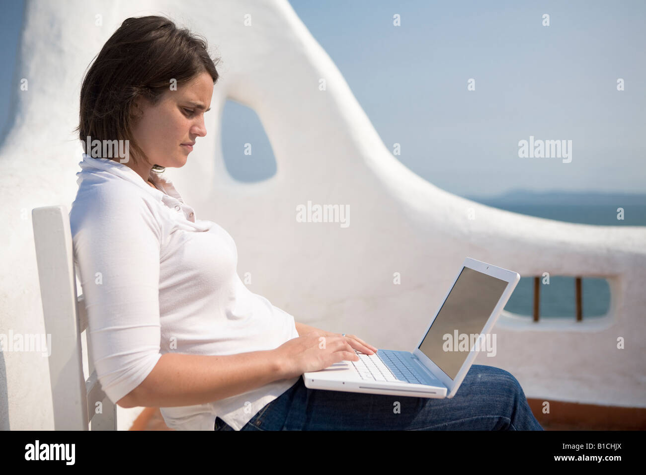 Junge Frau schreiben auf ihrem Macbook Laptop in eine mediterrane Terrasse im Casapueblo Punta del Este-Uruguay Stockfoto