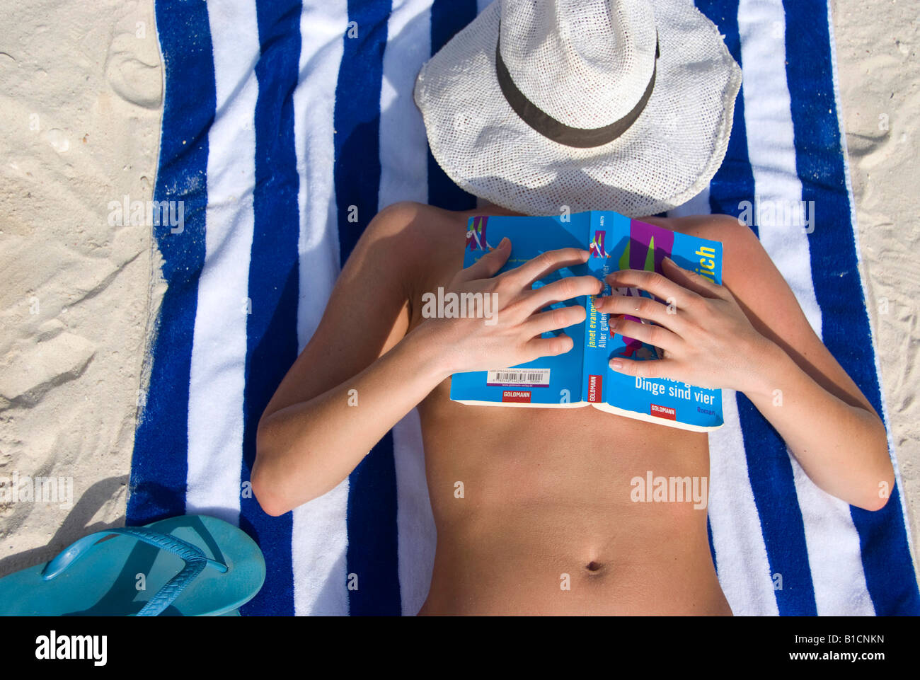 Frau mit Buch entspannen am Strand, ihr Gesicht geschützt durch eine Sonne, Philippinen Stockfoto