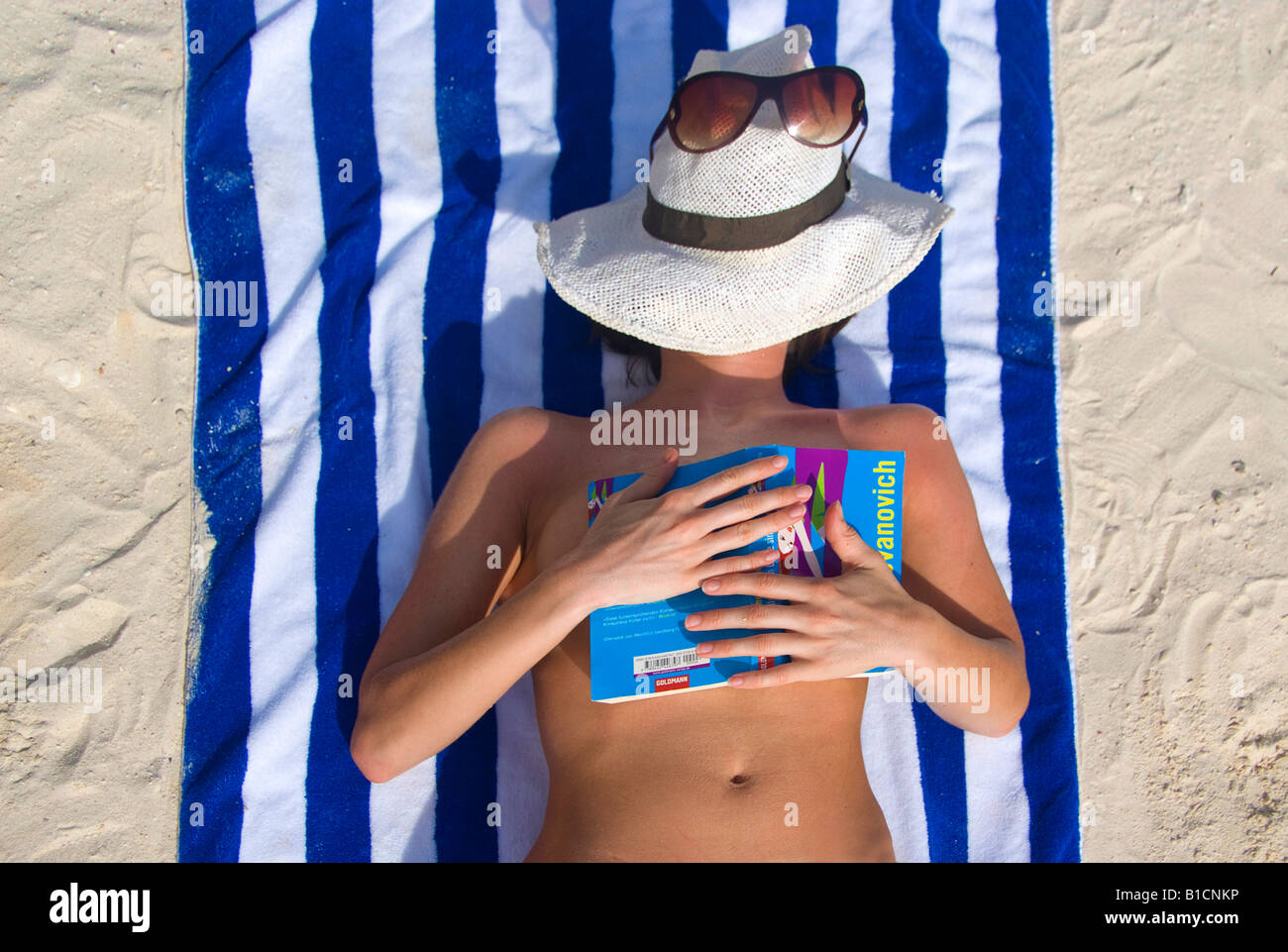 Frau mit Buch entspannen am Strand, das Gesicht geschützt durch einen Sonnenhut mit Sonnenbrille, Philippinen Stockfoto