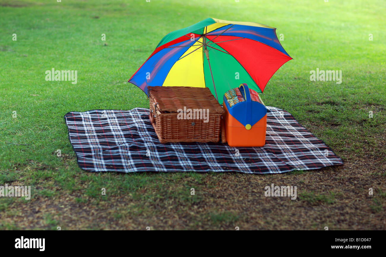 Picknickkorb, Decke, Kühlbox & Regenschirm, bei einem Picknick. Stockfoto