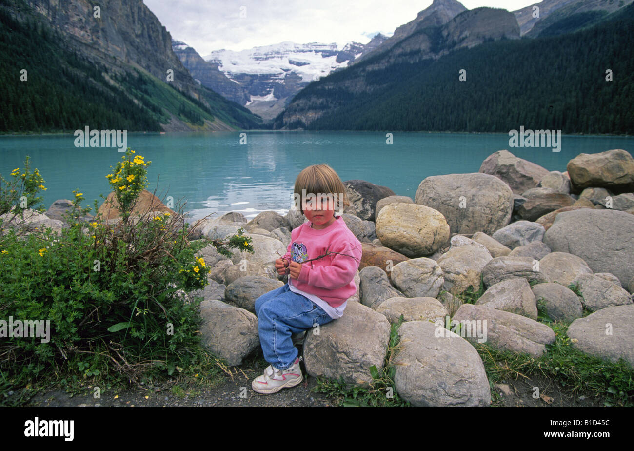 Ein junges Mädchen sitzt neben Lake Louise See gefärbt hellblau aus Sedimenten aus nahe gelegenen Gletscher Stockfoto