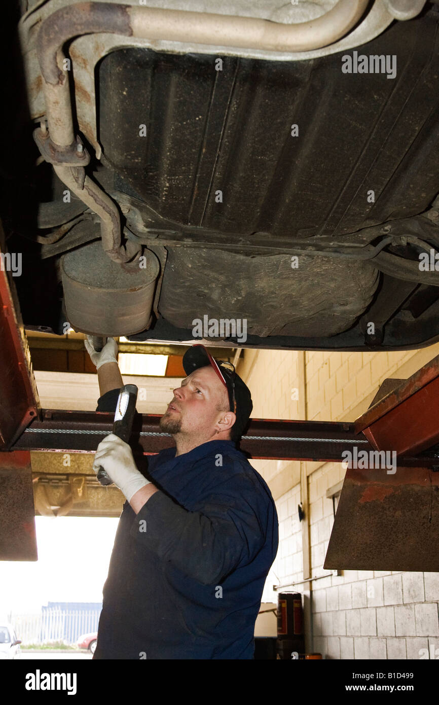 ein Mechaniker überprüft unter einem Auto während einer TÜV-Prüfung Stockfoto