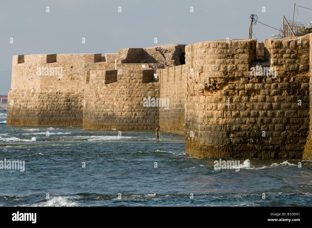 Fischer seine Netze zu sammeln, wie die Sonne am Fuße des die Zinnen des alten Kreuzfahrer Stadt Akko (Akko), Israel Stockfoto