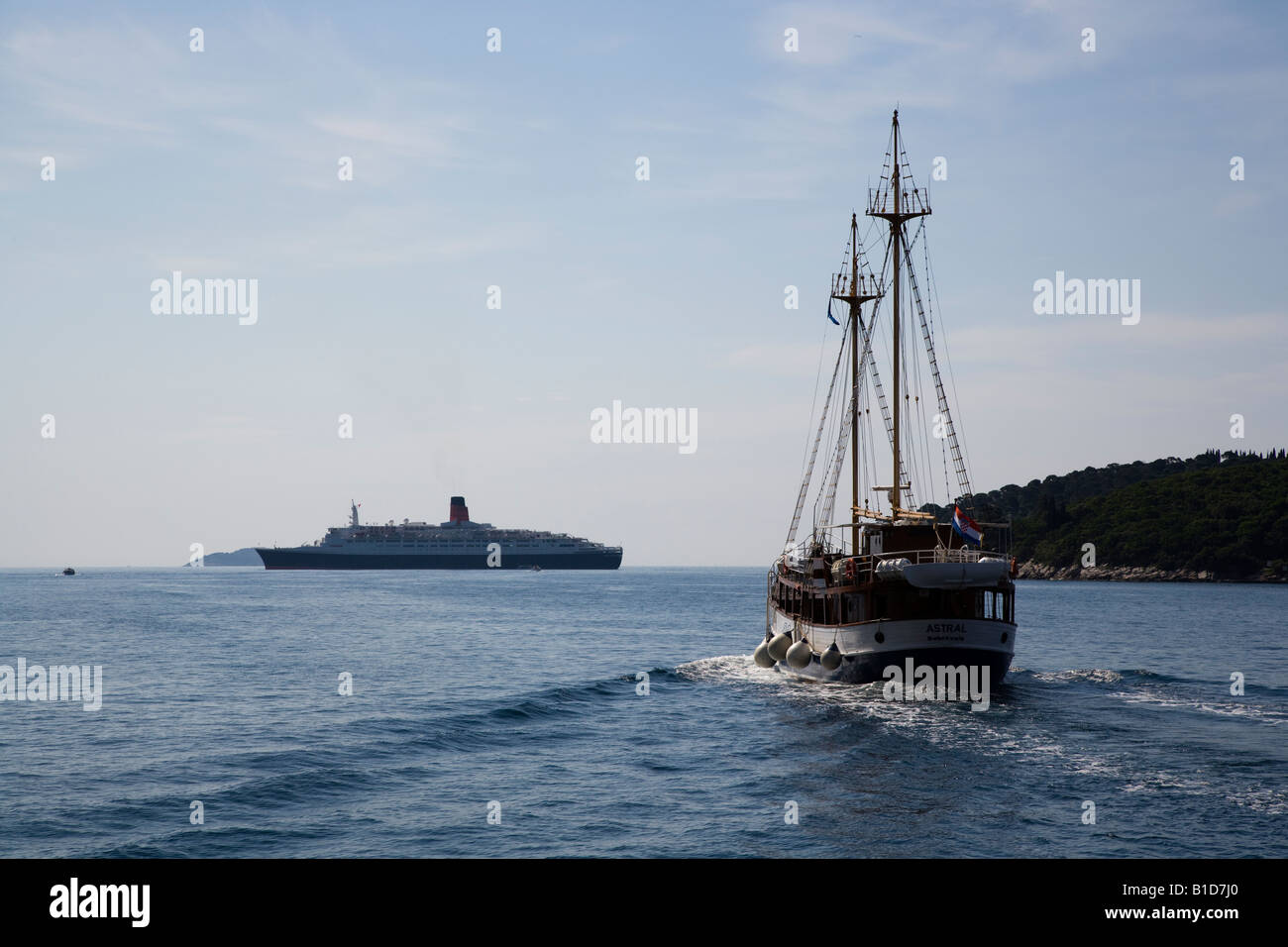 Das Segelschiff Astral verlassen Dubrovnik in Richtung Insel Lopud mit Cunard QE2 vor Anker Stockfoto