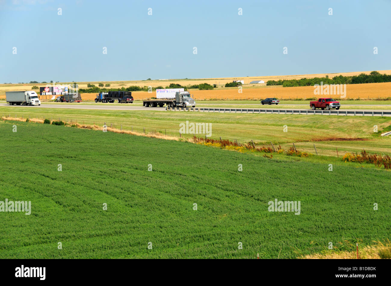 Interstate 40 in central Oklahoma, von der Lkw-Branche intensiv genutzt. Hier schneidet sie zwischen Weizen und Alfalfa Feldern. Oklahoma, USA. Stockfoto