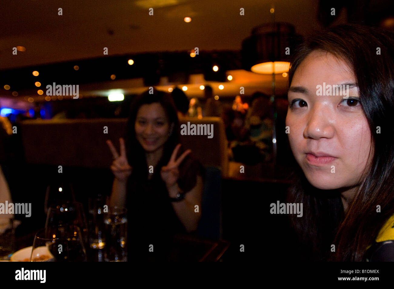 Bar-Szene mit zwei Hong Kong chinesische Frauen. Man macht ein typisches Hong Kong V-Zeichen mit Händen. Stockfoto