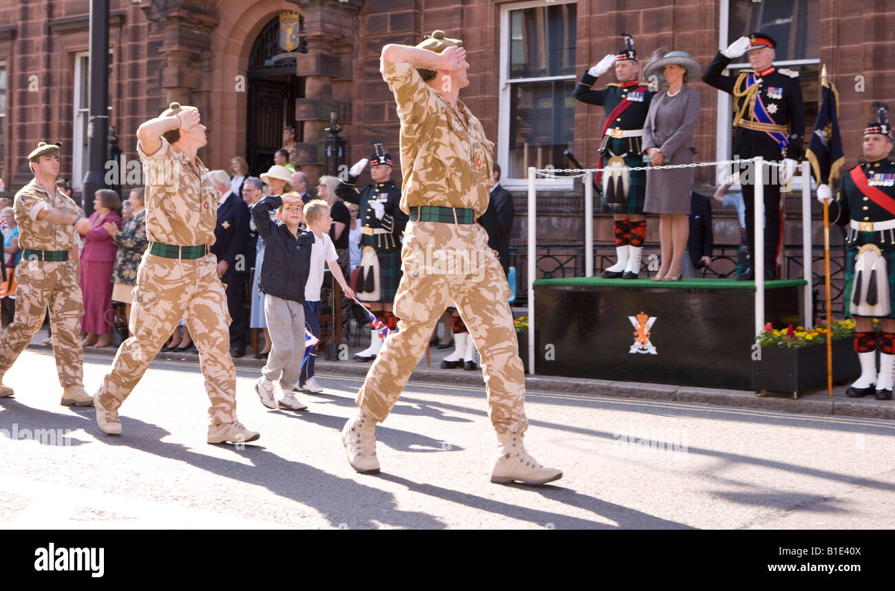Militär Soldaten des Royal Regiment of Scotland salutieren, da marschieren sie durch Dumfries mit Kindern imitiert Gruß Stockfoto