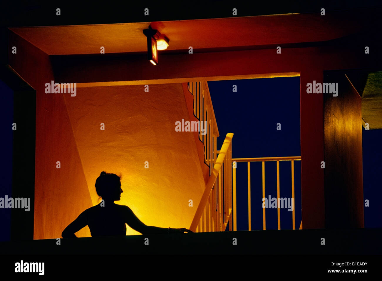 Frau im Abendkleid stehen im beleuchteten Treppenhaus @ Nacht USA Stockfoto