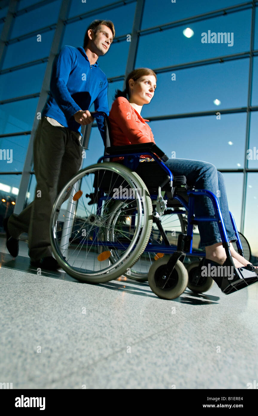 Seitenansicht eines Mitte erwachsenen Mannes treibt eine junge Frau in einem Rollstuhl sitzt Stockfoto