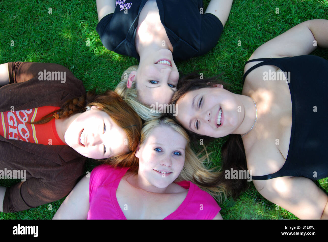 Junge Teenager Gruppe von Mädchen liegen auf dem Rasen, Bourton-on-the-Water, Gloucestershire, England, Vereinigtes Königreich Stockfoto