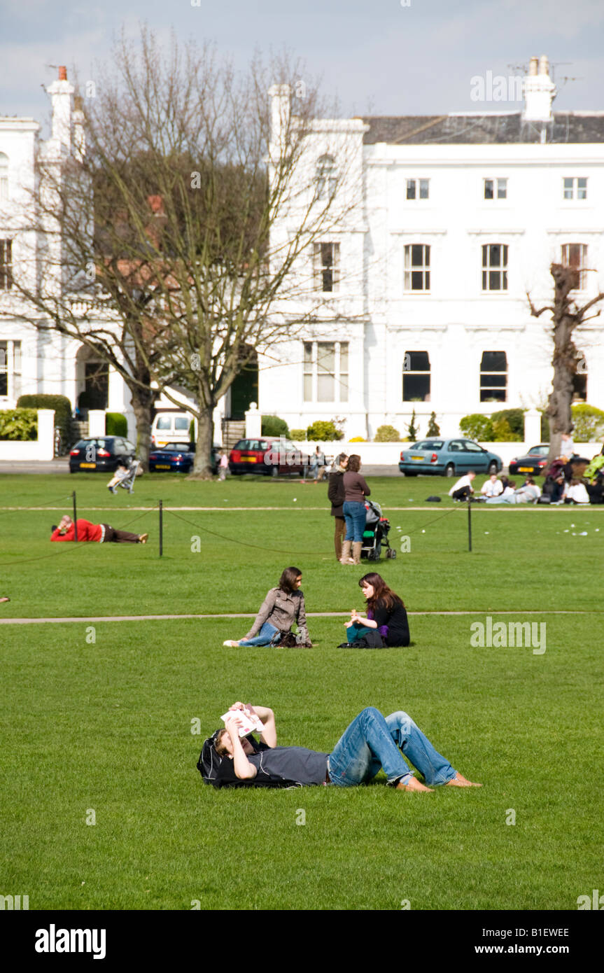 Menschen entspannen auf dem Rasen des Richmond Green, Richmond, Surrey, England Stockfoto