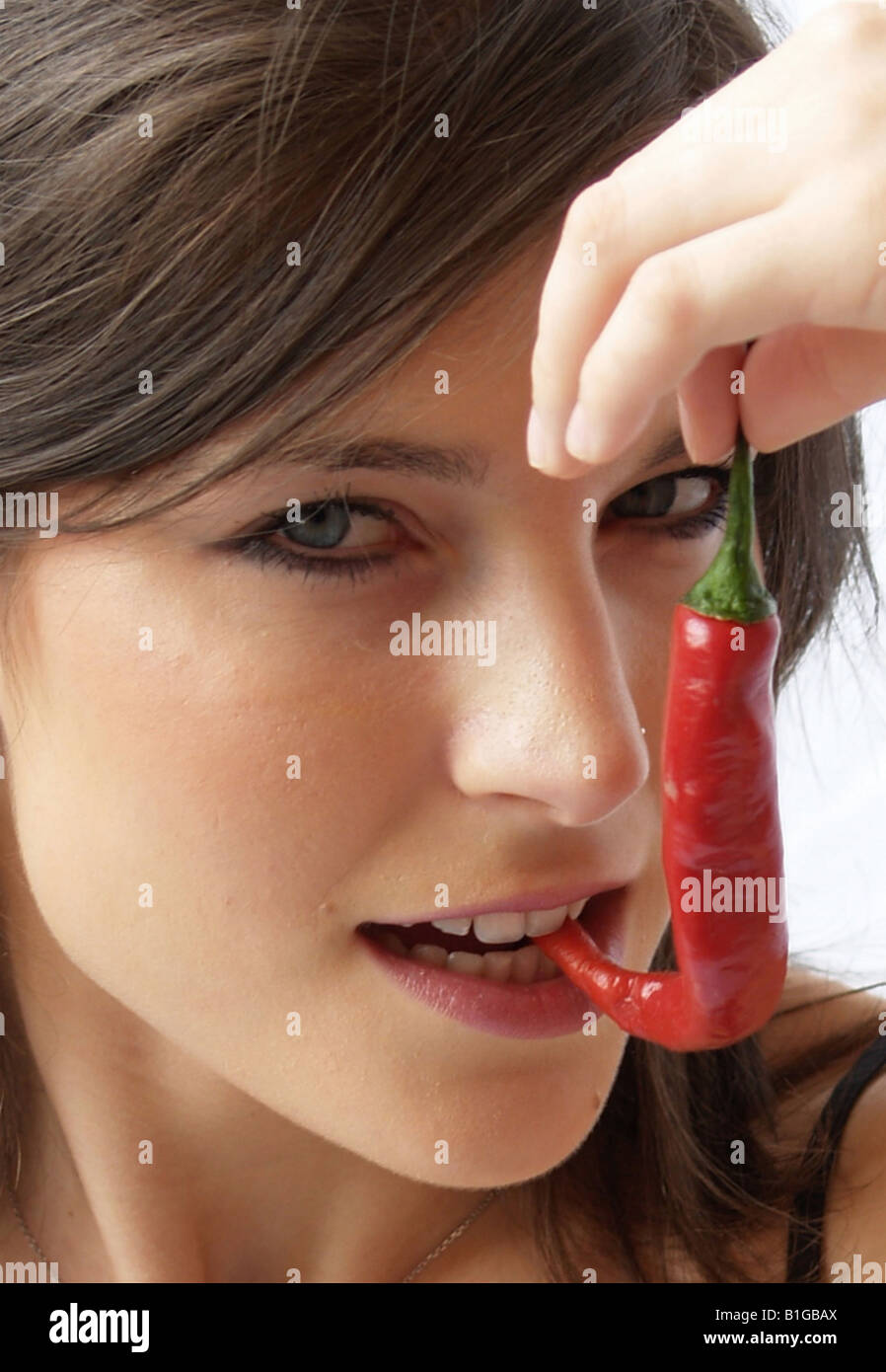 Nahaufnahme einer Frau, indem ein roter Pfeffer in den Mund Stockfoto