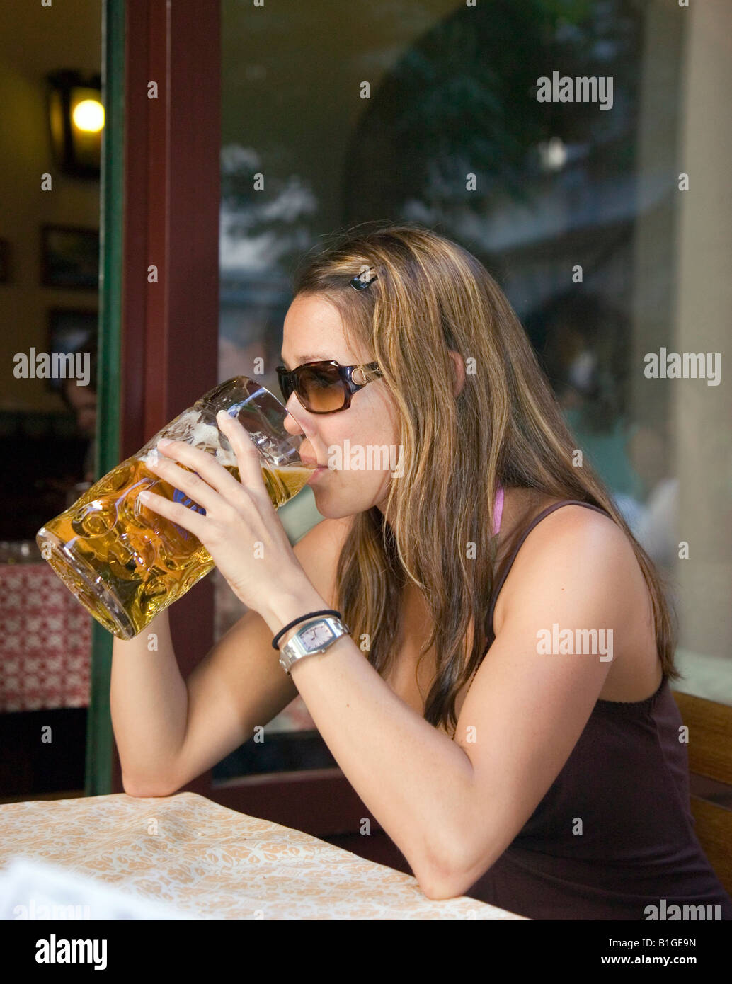 Hispanische 26-jährige Frau trinkt aus einem riesigen Glas Bier auf das ...