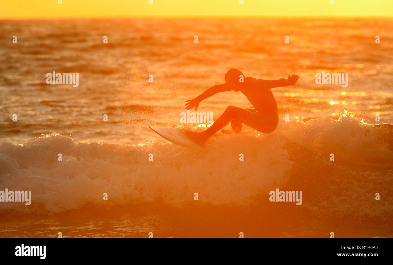 Eine Surfer reitet die Wellen am Abend den Sonnenuntergang über Sennen Beace in Corwall, UK. Stockfoto