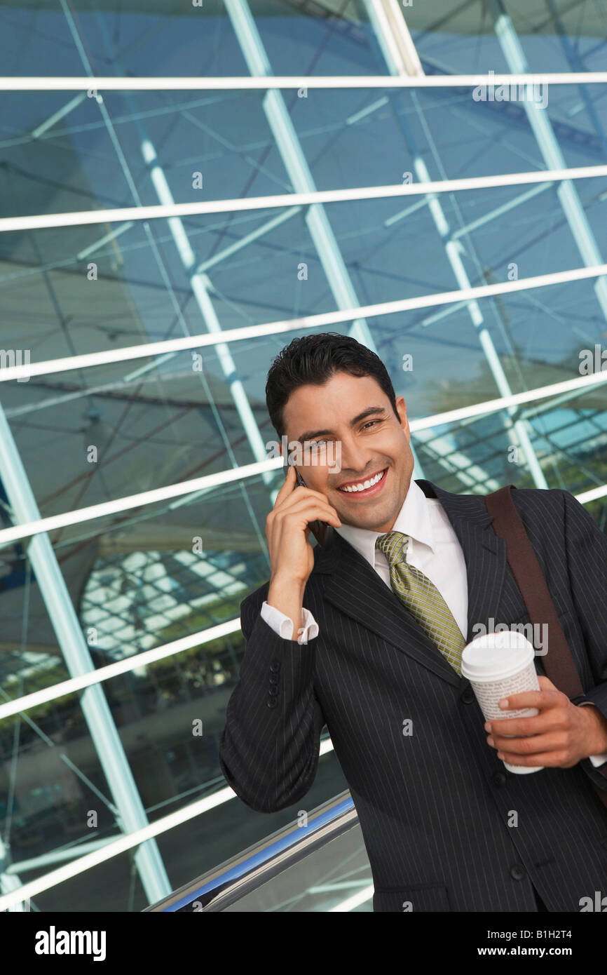 Geschäftsmann mit Mobiltelefon mit Take away Kaffee vor Bürogebäude Stockfoto