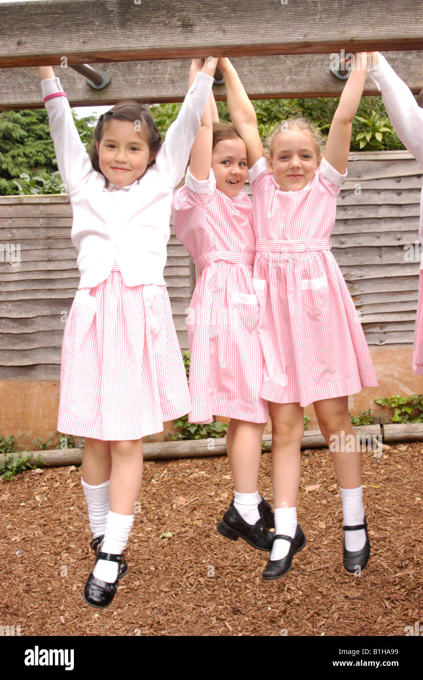 drei Mädchen von einem Klettergerüst auf einem Schulhof hängen Stockfoto