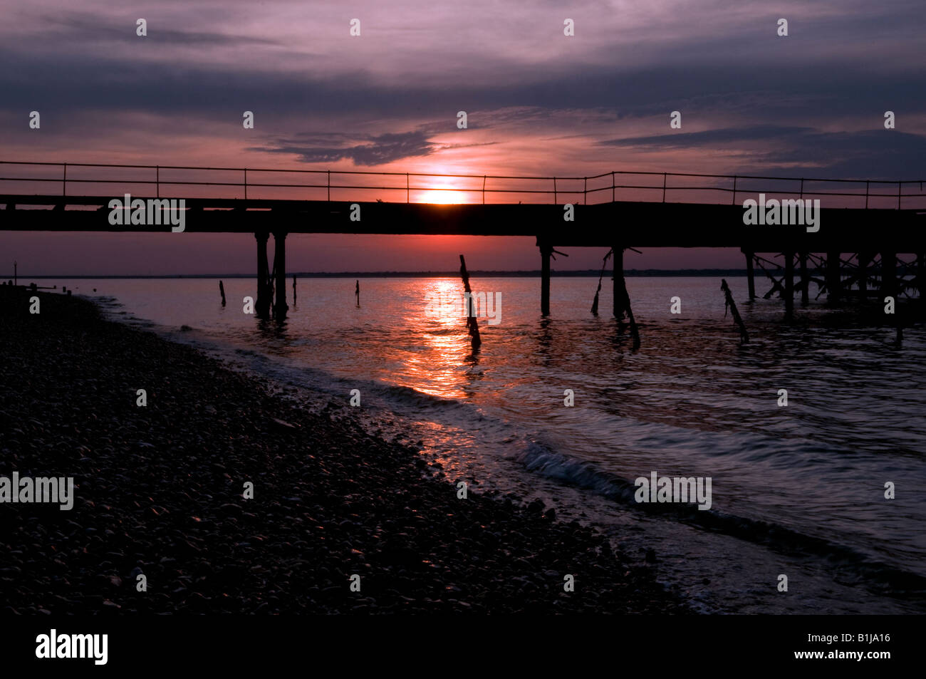Sun Set Nordküste der Yarmouth Küste Isle Of Wight, England UK mit einem alten Pier im Vordergrund in der silhouette Stockfoto