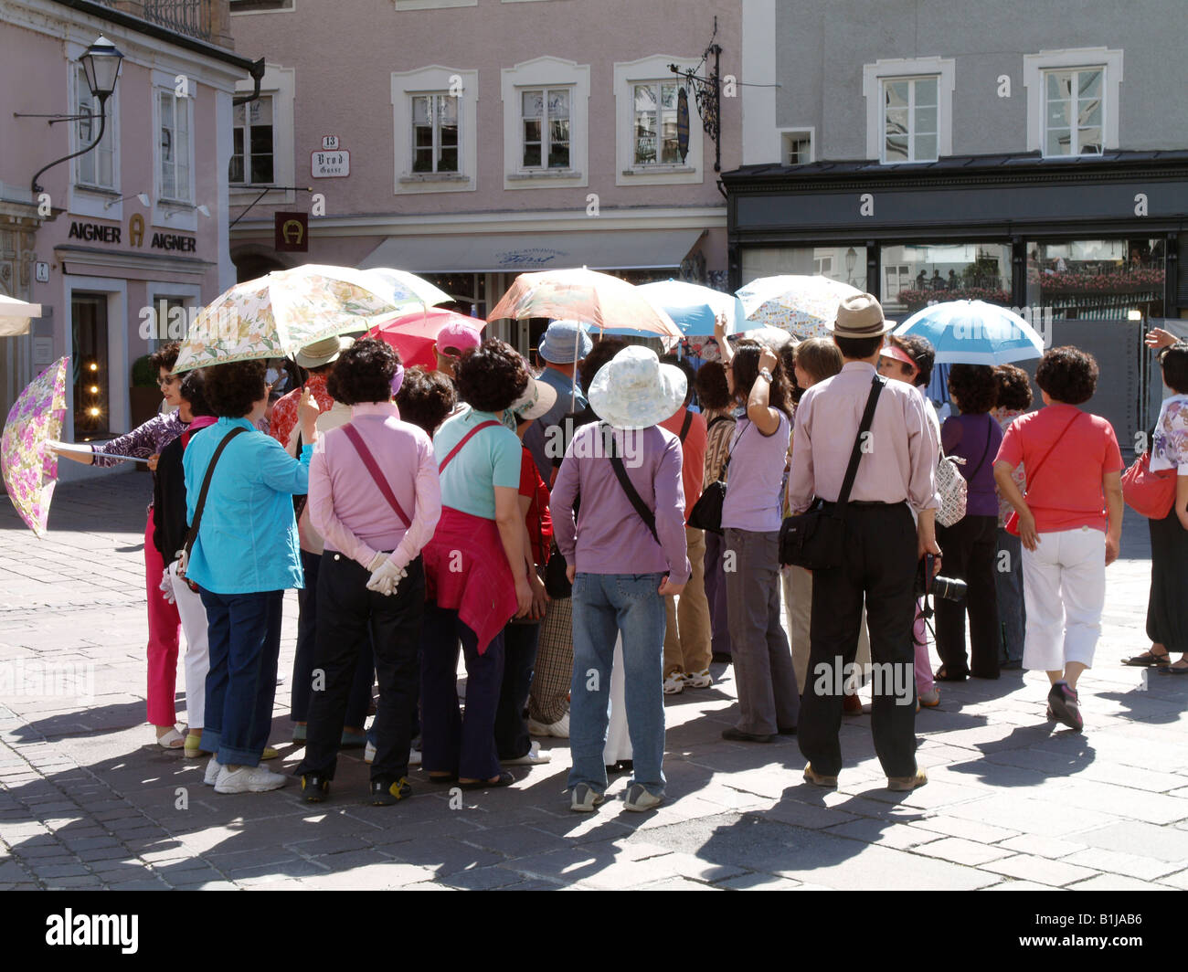 Asiatische Reisegruppe mit Sonnenschirmen, Besuch der alten Stadt Zentrum, Österreich, Salzburg Stockfoto