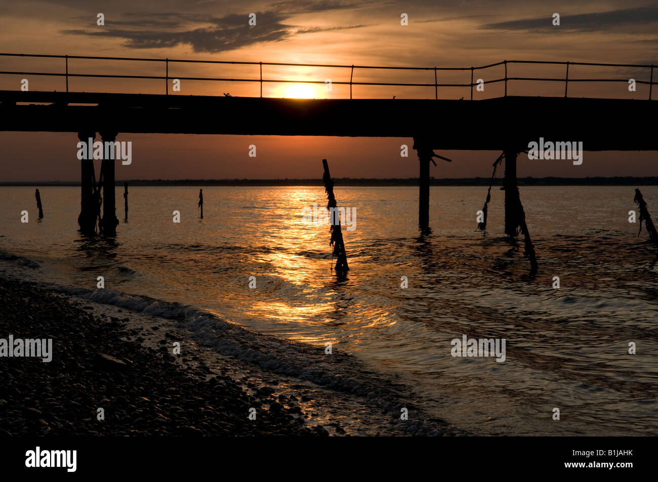Sun Set Nordküste der Yarmouth Küste Isle Of Wight, England UK mit einem alten Pier im Vordergrund in der silhouette Stockfoto