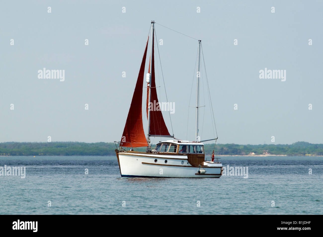weiße Segelboot mit einem roten Segel auf dem Meer Ozean Stockfoto