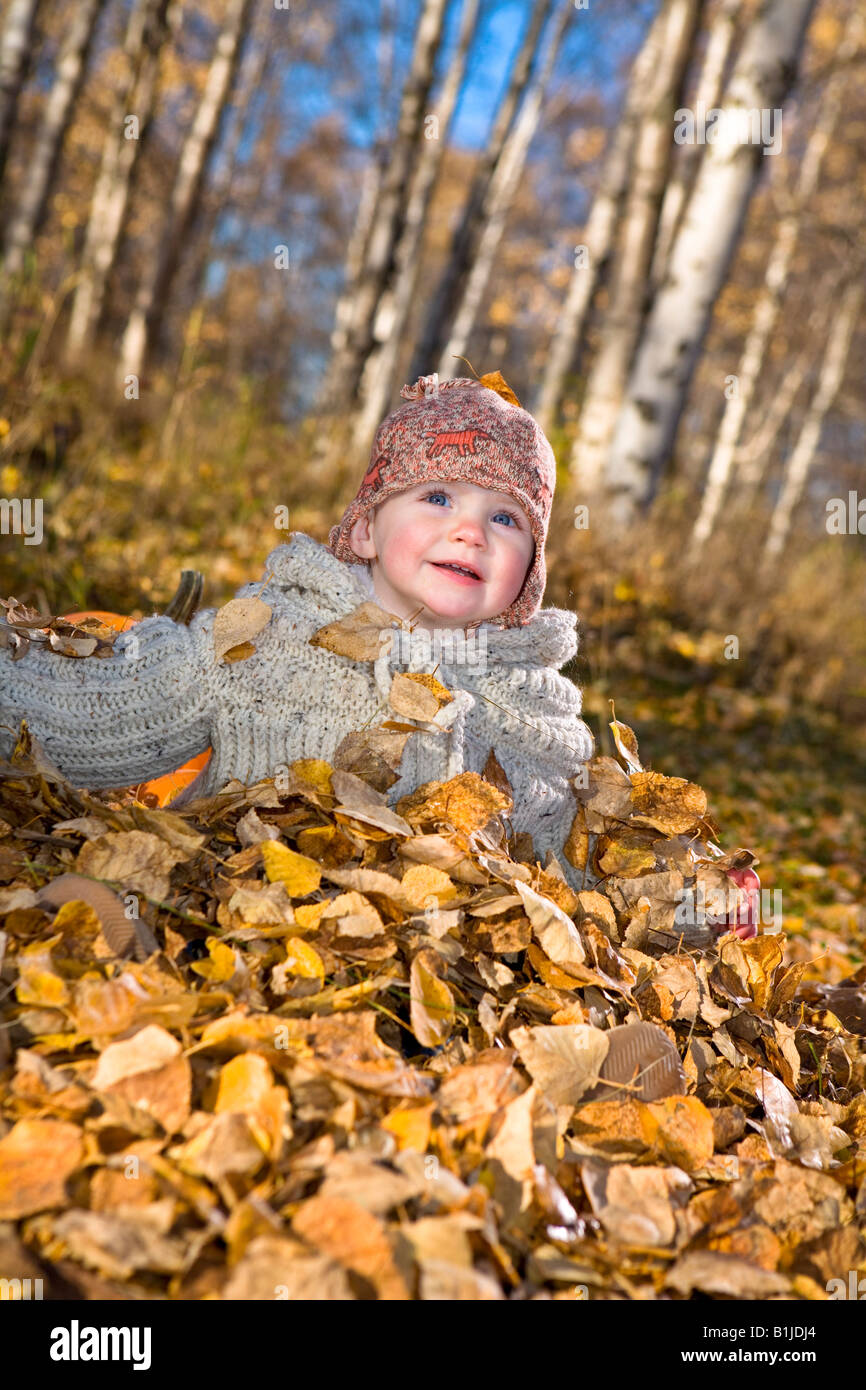 Junges Mädchen Kleinkind spielen im Herbst Blätter neben Kürbisse in einem Waldgebiet von Anchorage in Alaska Yunan Stockfoto