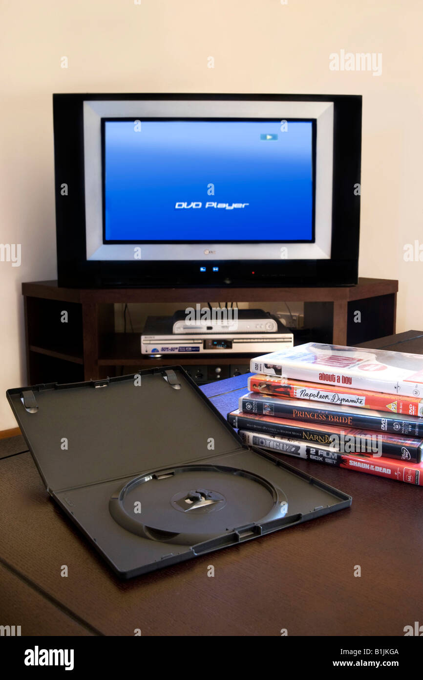 Ein Haufen von DVD-Filmen mit Fernseher und DVD-Player im Hintergrund Stockfoto