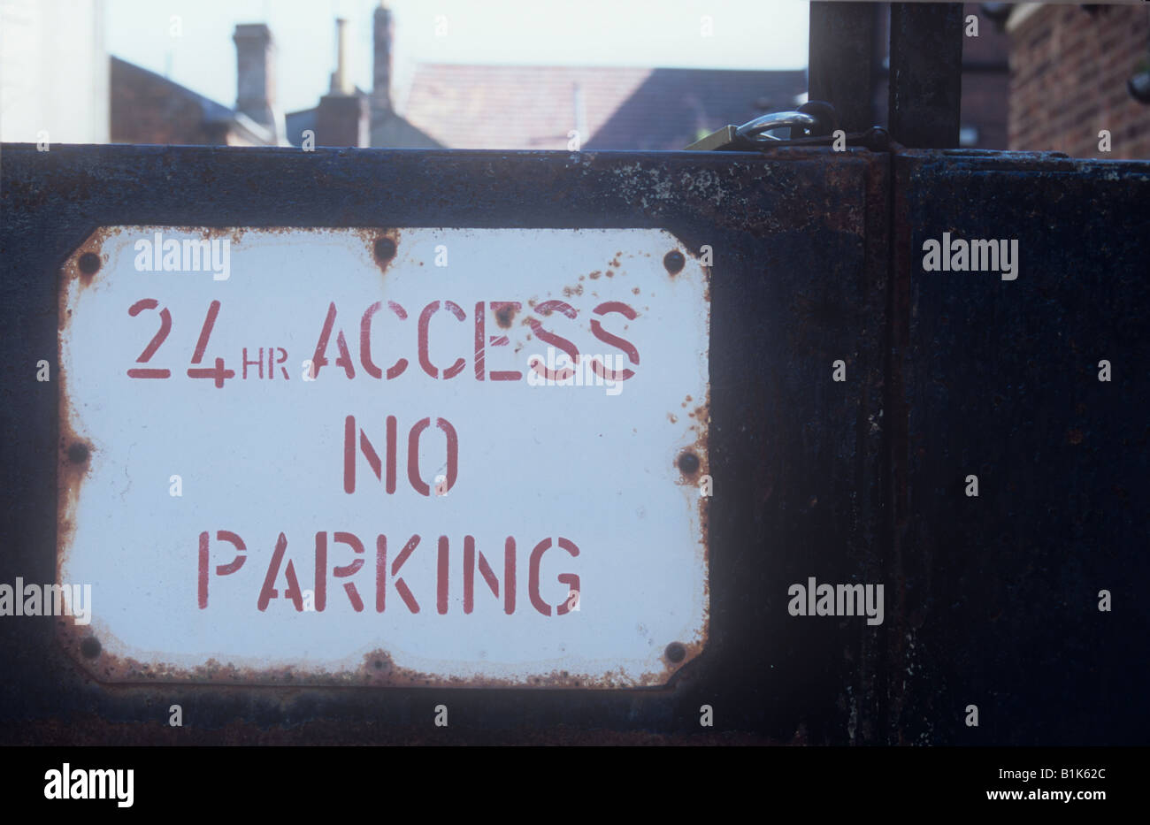 Rote und weiße Hinweis auf Rosten Vollmetall und Vorhängeschloss Tore unter Angabe der 24-Stunden Zugang Parkverbot mit Dächern sichtbar über Stockfoto