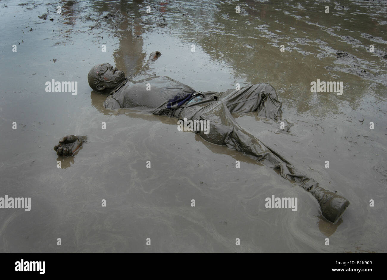 Ein Mann liegt in einer schlammigen Pfütze während des Glastonbury Festivals Stockfoto