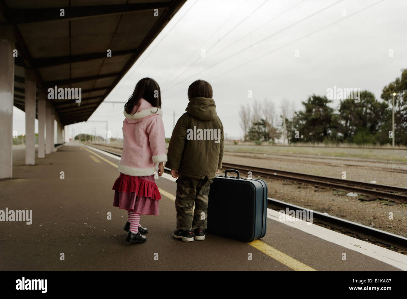 Jungen im Alter von sechs und Schwester im Alter von vier warten auf den Zug auf der Plattform am Bahnhof von Palmerston North New Zealand Stockfoto