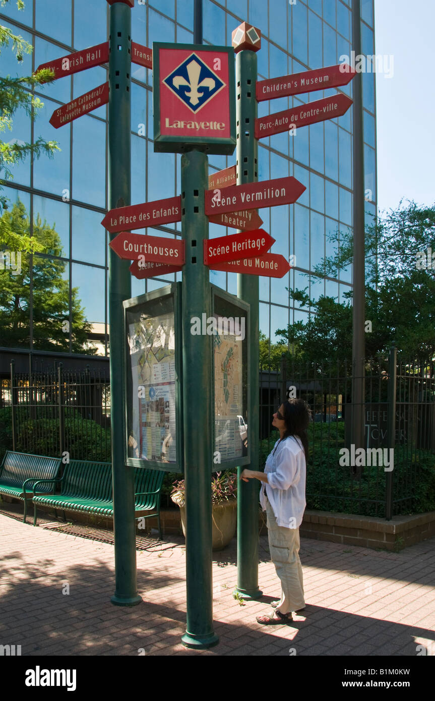 Frau schaut Punkte von Interesse Wegweisern Zentrum von Lafayette, Louisiana Stockfoto