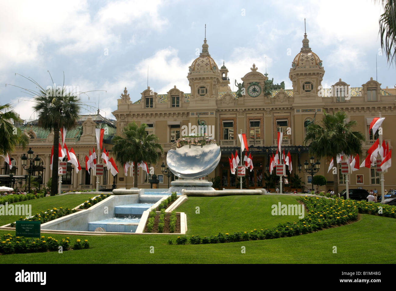 Das Casino MONACO in Monte Carlo eröffnet im Jahre 1878. Ein riesiger Spiegel steht in den Gärten vor flankiert von der Monaco-Flagge Stockfoto