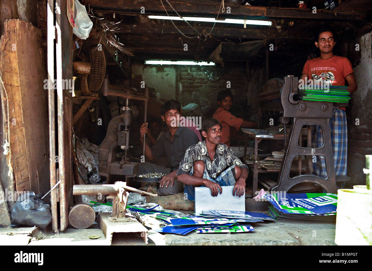 Indien MUMBAI MAHARASHTRA Arbeitnehmer im Ladengeschäft Metallfertigung posieren stolz wie sie Metalldosen und Zeichen für das recycling zerschnitten Stockfoto