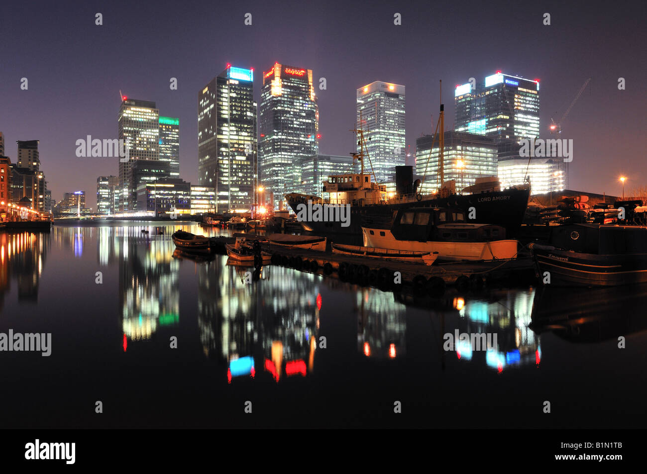 Schiff und Boote vertäut am West India Docks, mit Canary Wharf Finanzviertel im Hintergrund Stockfoto