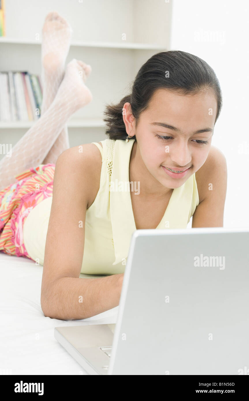 Mädchen auf dem Bett liegend und mit einem laptop Stockfoto