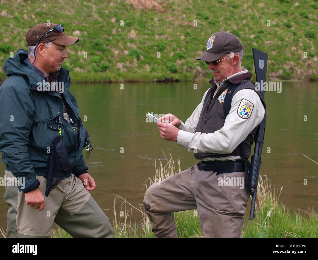 US federal Fische und andere Tierarten Offizier prüft Fischers Angelschein. Stockfoto