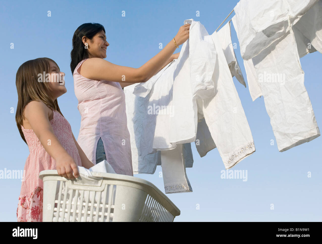 Niedrigen Winkel Ansicht einer Mitte Erwachsene Frau und ihrer Tochter hängende Kleidung auf einer Wäscheleine Stockfoto