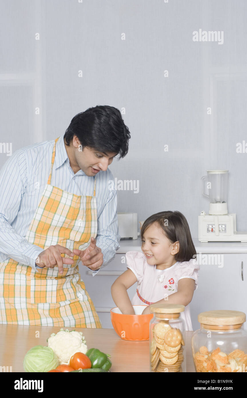 Junger Mann, Blick auf seine Tochter, die Zubereitung von Speisen Stockfoto
