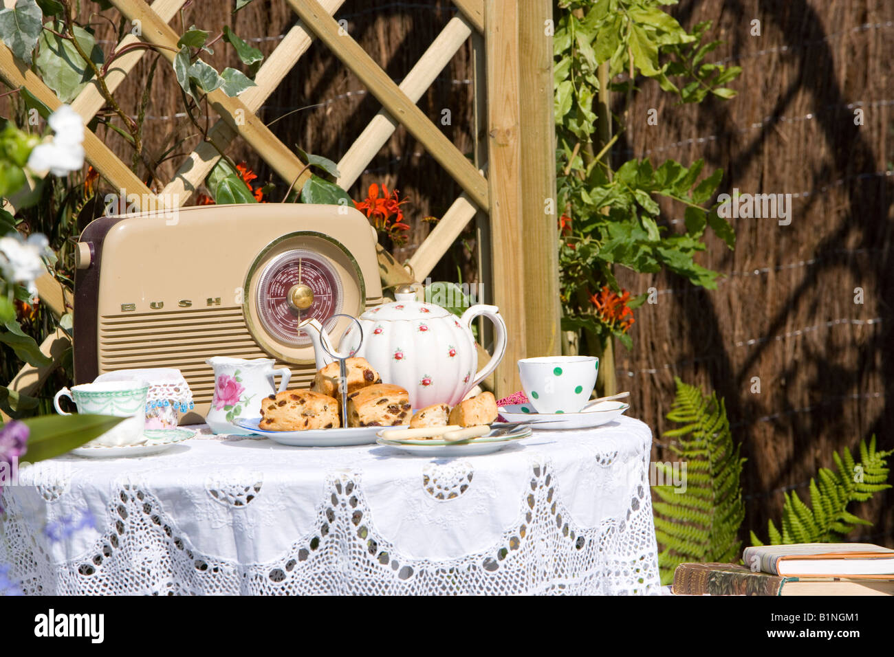 Nachmittagstee und Kuchen auf einem kleinen Gartentisch mit einem Busch-radio Stockfoto