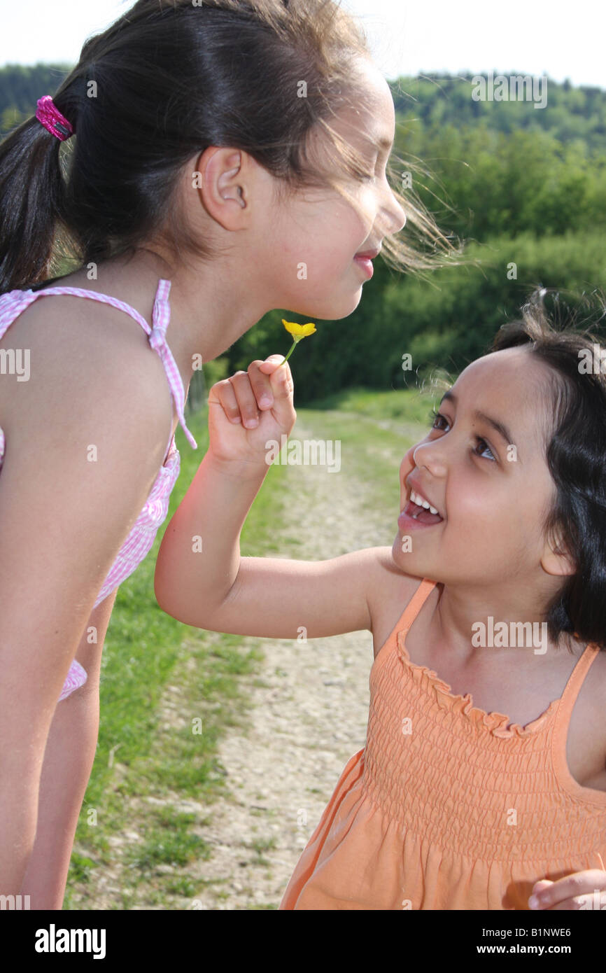 Zwei Schwestern spielen mit Ranunkeln in der englischen Landschaft. Stockfoto